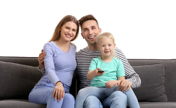 Happy young family watching TV while sitting on sofa against white background — ストック写真