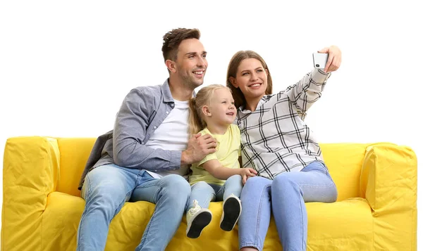 Feliz jovem família tomando selfie no sofá contra fundo branco — Fotografia de Stock