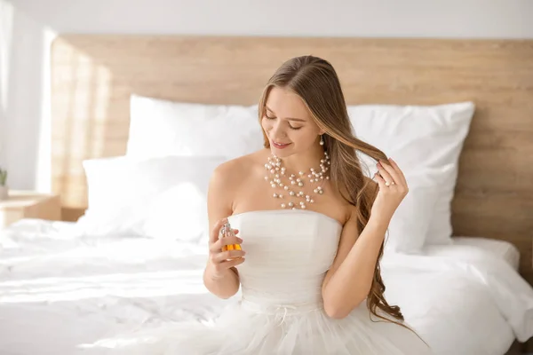 Beautiful young bride with bottle of perfume at home — Stock Photo, Image