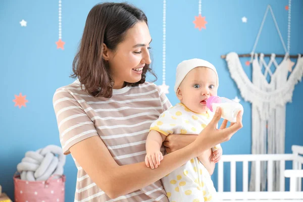 Mother feeding baby with milk from bottle at home — Stock Photo, Image