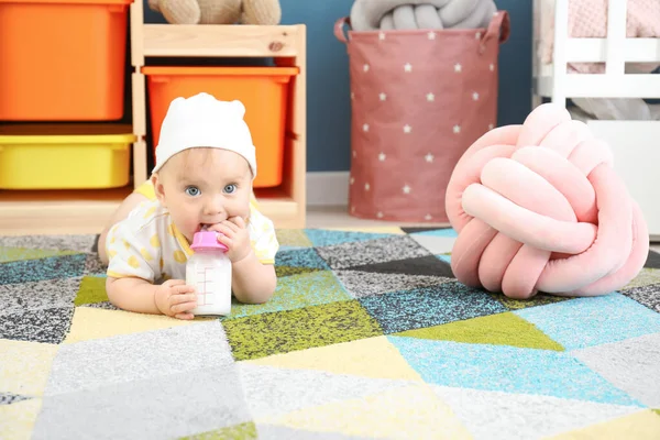 Cute baby drinking milk from bottle at home — Stock Photo, Image
