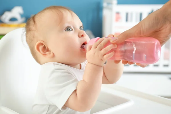 Madre dando a pequeño biberón de agua en casa — Foto de Stock