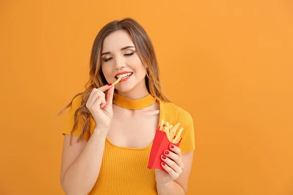 Portret van mooie jonge vrouw met frites op kleur achtergrond — Stockfoto
