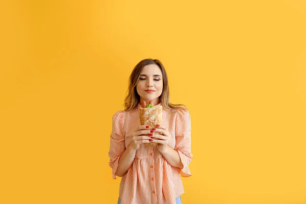 Portrait de belle jeune femme avec hot dog français sur fond de couleur — Photo