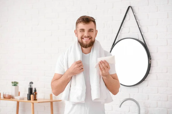 Handsome young man with tube of cream in bathroom — Stock Photo, Image