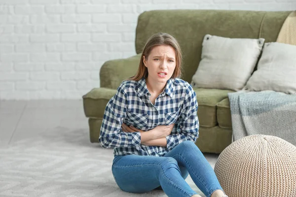 Giovane donna che soffre di dolore addominale a casa — Foto Stock