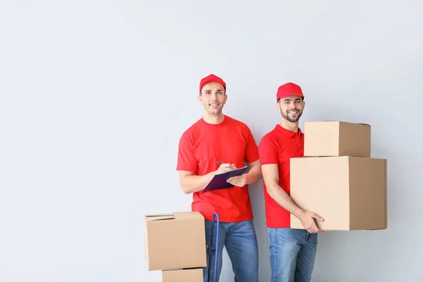 Delivery men with boxes on light background