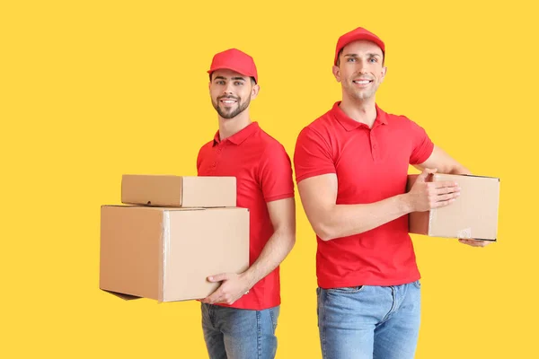 Delivery men with boxes on color background