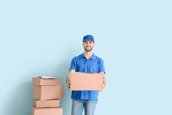 Delivery man with boxes on color background