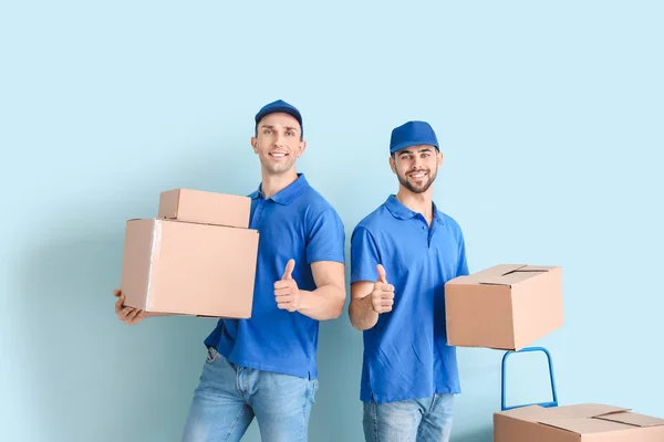 Entrega de homens com caixas mostrando polegar para cima em fundo de cor — Fotografia de Stock