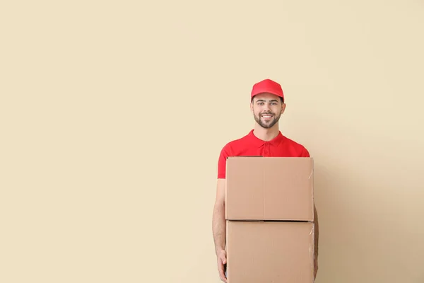 Delivery man with boxes on color background — Stock Photo, Image
