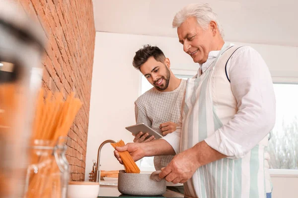 Jongeman en zijn vader koken in de keuken — Stockfoto