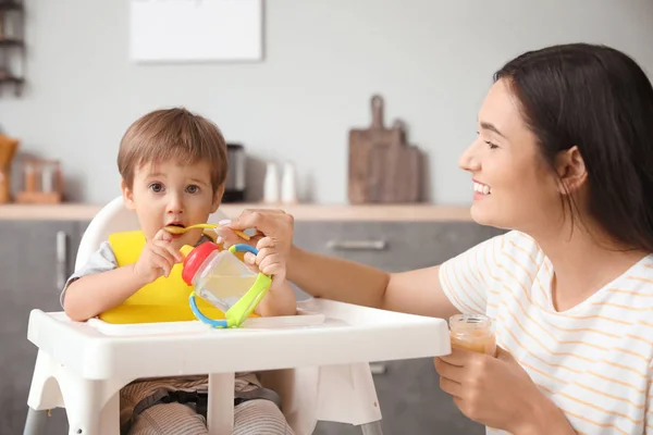 Matka krmí svého malého syna v kuchyni — Stock fotografie