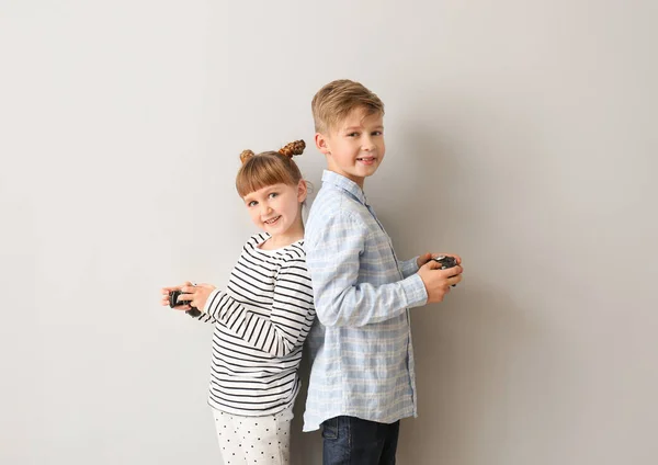 Små barn som spelar tv-spel på grå bakgrund — Stockfoto