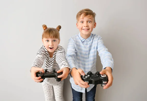 Kleine Kinder spielen Videospiele auf grauem Hintergrund — Stockfoto