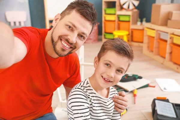 Padre y su pequeño hijo se toman selfie mientras montan muebles en casa —  Fotos de Stock