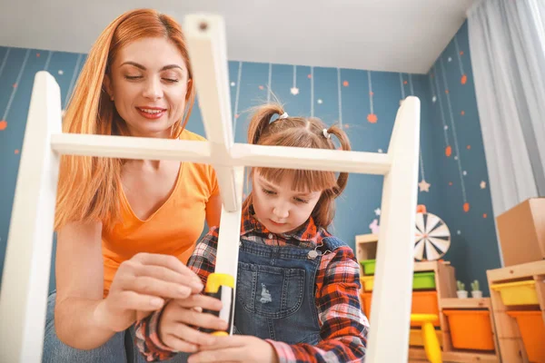 Mother and her little daughter assembling furniture at home — Stock Photo, Image