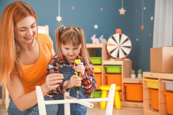 Mother and her little daughter assembling furniture at home — Stock Photo, Image