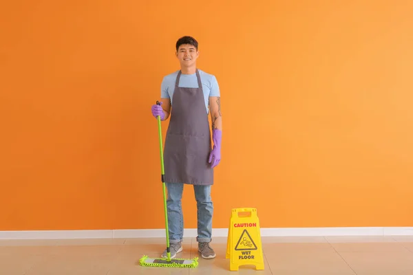 Aziatische conciërge met vloer dweil in de buurt kleur muur — Stockfoto