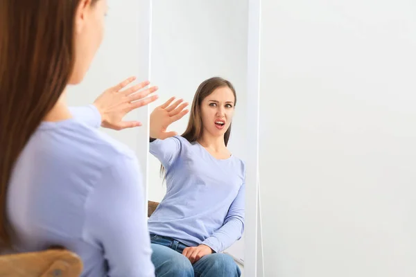 Descontente jovem mulher olhando no espelho em casa — Fotografia de Stock