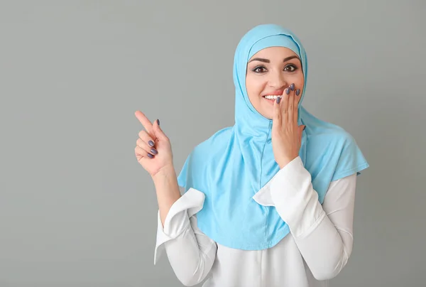Красивая арабская женщина указывает на что-то на сером фоне — стоковое фото
