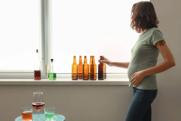 Mladá těhotná žena s alkoholem doma — Stock fotografie