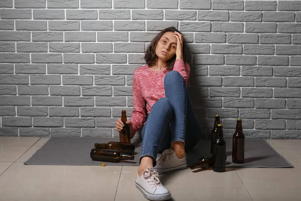 Joven borracha cerca de la pared de ladrillo. Concepto de alcoholismo — Foto de Stock