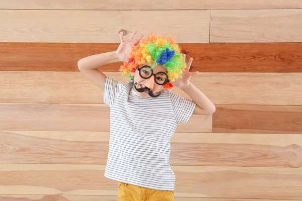 Kleiner Junge in lustiger Verkleidung auf Holzgrund. Aprilscherz-Fest — Stockfoto