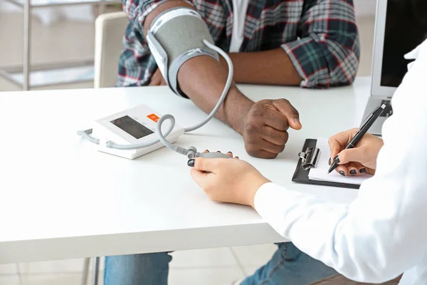 Female cardiologist examining male patient in clinic — Stock Photo, Image