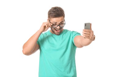 Genç adam beyaz arka planda selfie çekiyor.