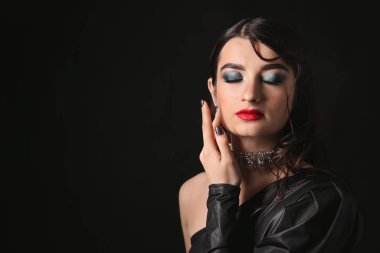 Karanlık arka planda güzel, modaya uygun bir kadın.