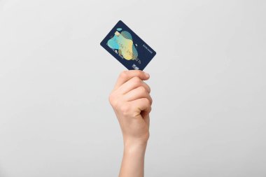 Female hand with credit card on light background
