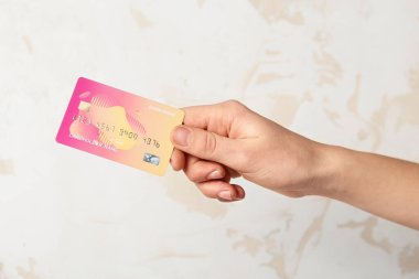 Female hand with credit card on light background