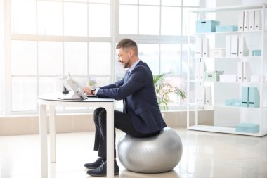 İş adamı ofiste çalışırken spor salonunda oturuyor.