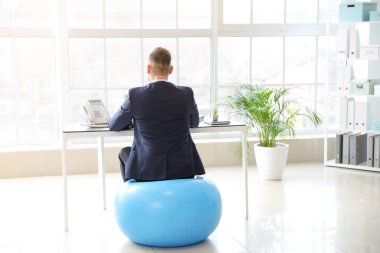 İş adamı ofiste çalışırken spor salonunda oturuyor.