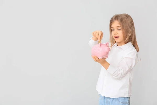 Linda chica poniendo dinero en alcancía sobre fondo blanco — Foto de Stock