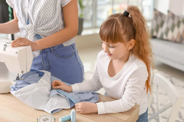 Kleine Tochter hilft ihrer Mutter in Schneiderei — Stockfoto