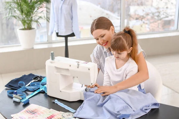 Kleine Tochter hilft ihrer Mutter in Schneiderei — Stockfoto