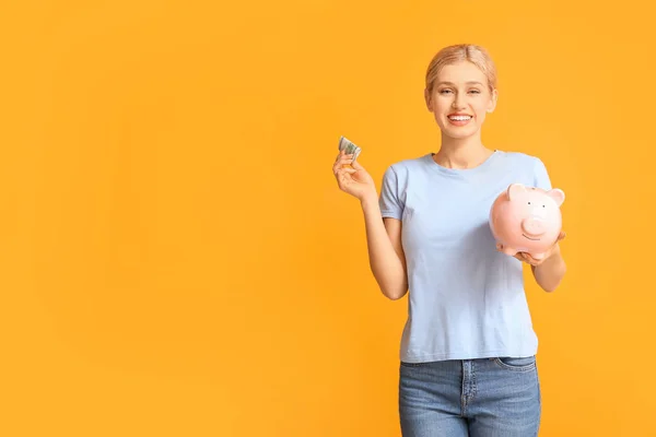 Jonge vrouw met spaarvarken op kleur achtergrond — Stockfoto