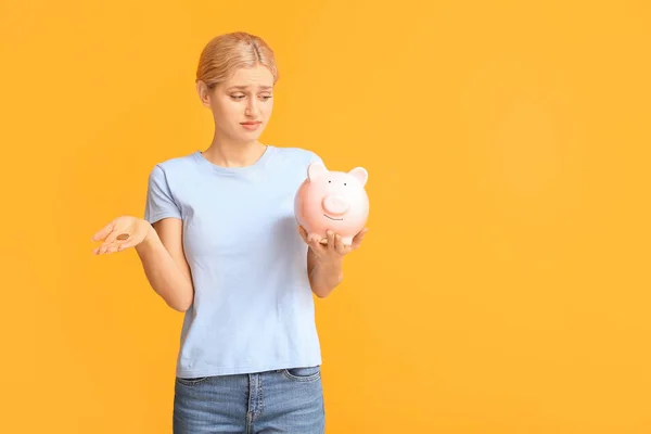 Sad woman with piggy bank on color background — Stock Photo, Image