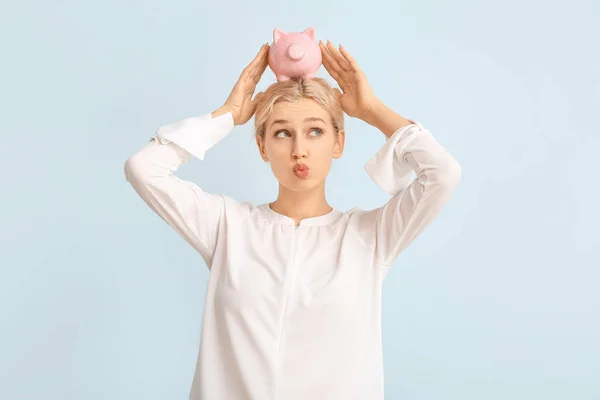 Young woman with piggy bank on color background — Stock Photo, Image