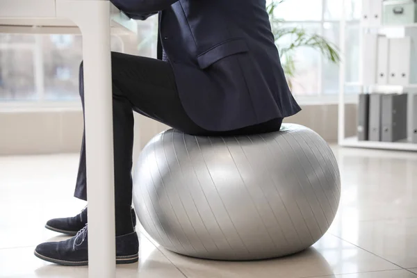 Businessman sitting on fitness ball while working in office — Stock Photo, Image