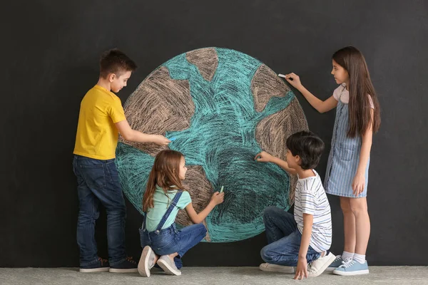 Little children drawing planet on dark background. Earth Day celebration