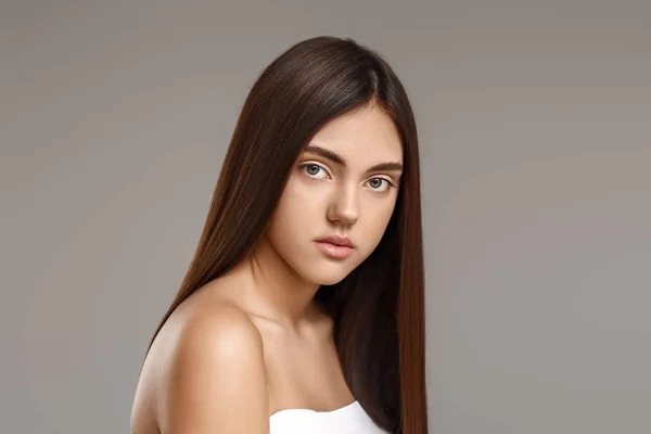 Junge Frau mit schönen glatten Haaren auf grauem Hintergrund — Stockfoto