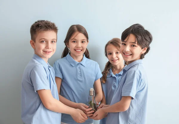 Petits enfants tenant ampoule avec plante sur fond de couleur. Journée de la Terre — Photo