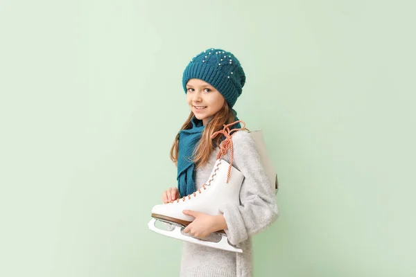 Petite fille mignonne avec des patins à glace sur fond de couleur — Photo