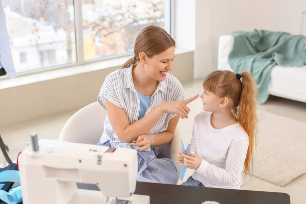 Little daughter helping her mother in tailor's workshop — Stock Photo, Image