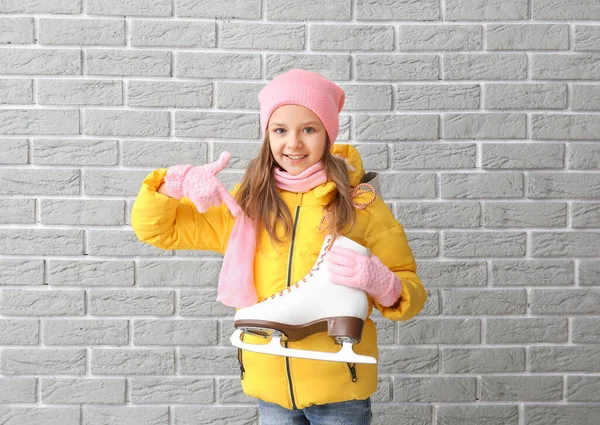 Linda niña con patines de hielo sobre fondo de ladrillo gris — Foto de Stock