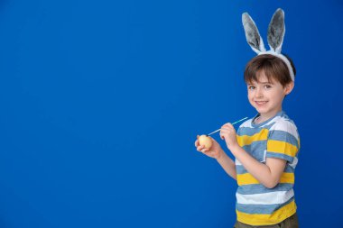 Paskalya yumurtası ve renk arkaplanı olan küçük bir çocuk.