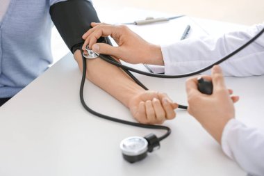 Kadın hastayı klinikte muayene eden erkek kardiyolog.